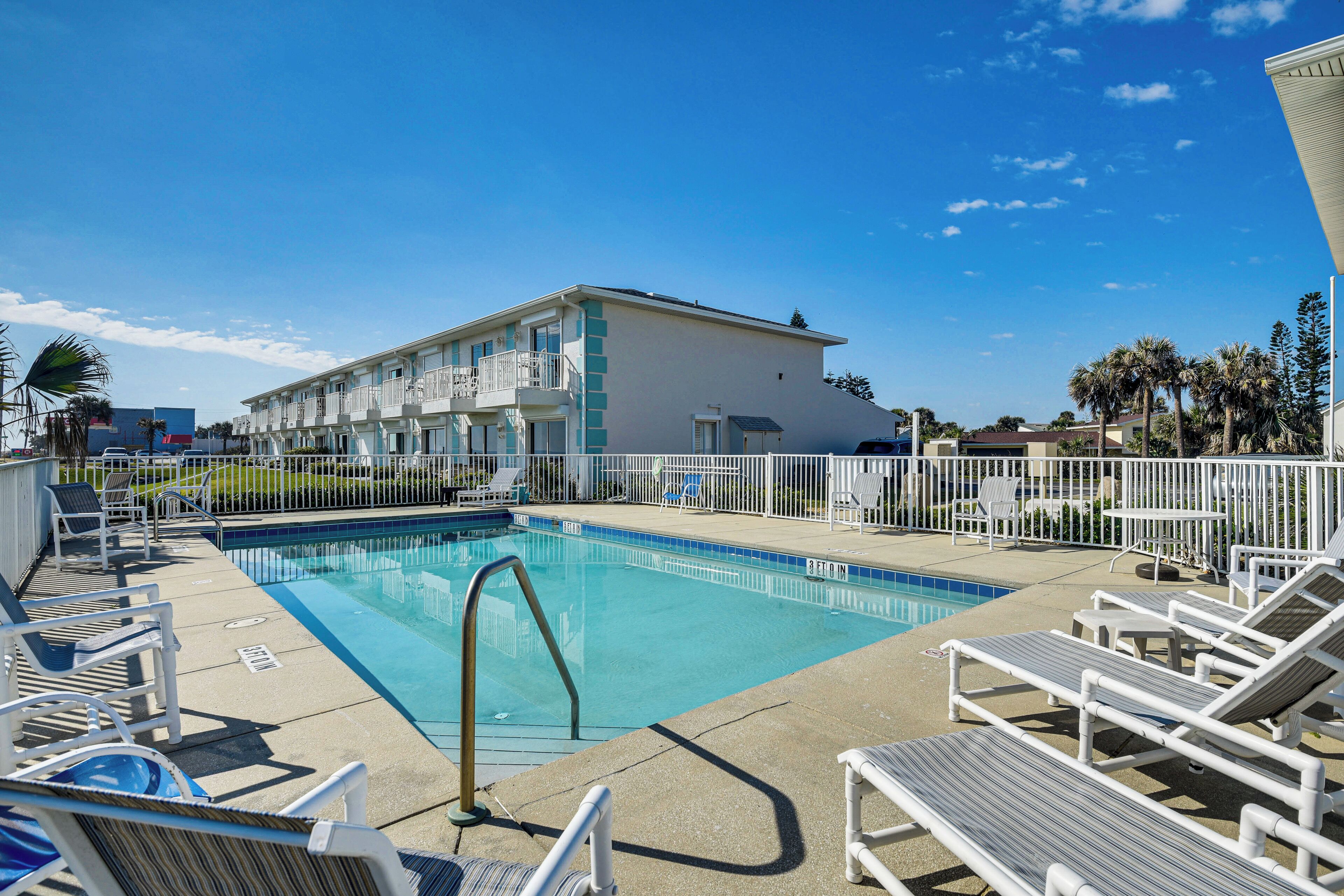 A swimming pool with lounge chairs and a building in the background.