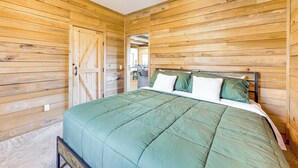 Een kamer met houten lambrisering, een bed, een deur en een plafondventilator.
