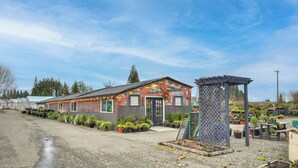 Un bâtiment à la façade métallique et doté d’un espace extérieur abrité agrémenté de plantes en pot.