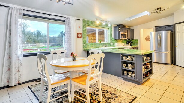 Une cuisine moderne avec un coin repas, comprenant un grand îlot central, un réfrigérateur et une vue sur l’extérieur.