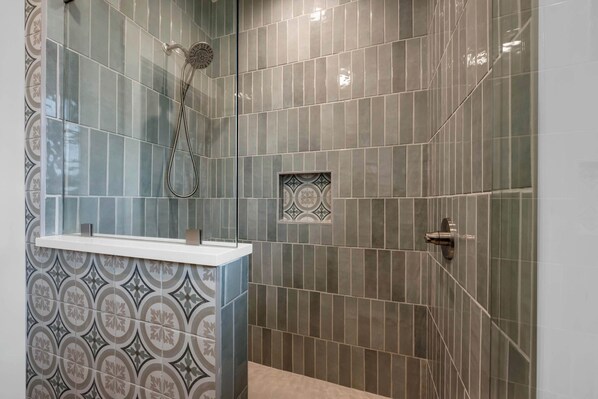 A shower with a handheld showerhead, a small window, and a decorative tile pattern on the wall. - Pecan Sandy - Lakefront home w/ views and kayaks! (Kingsland)
