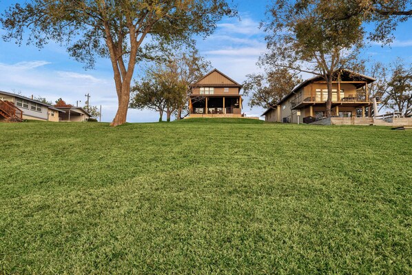 A two-story house with a large front porch, surrounded by trees and a grassy lawn.