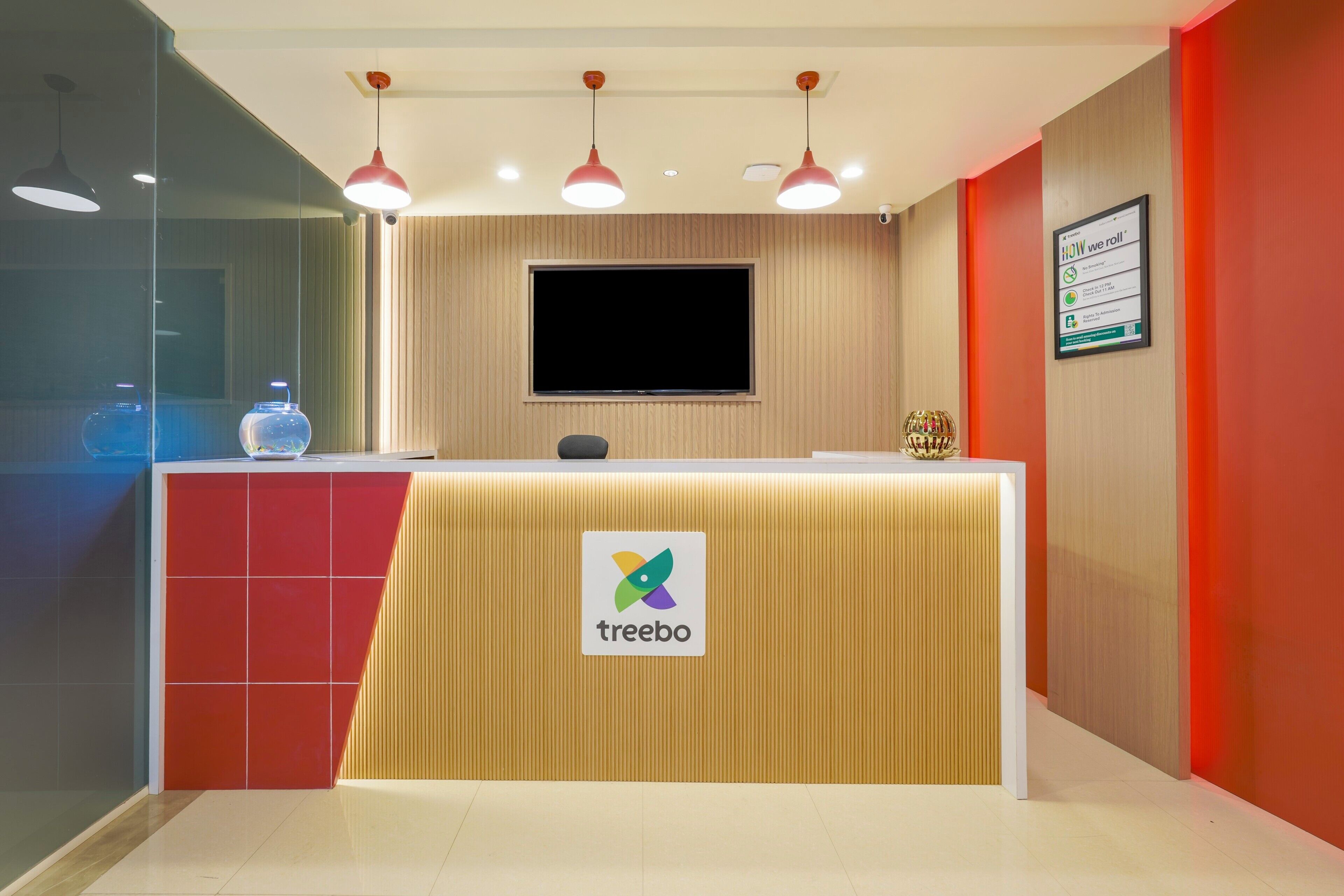 Una recepción con un logotipo, un televisor de pantalla plana y un cartel enmarcado en la pared.