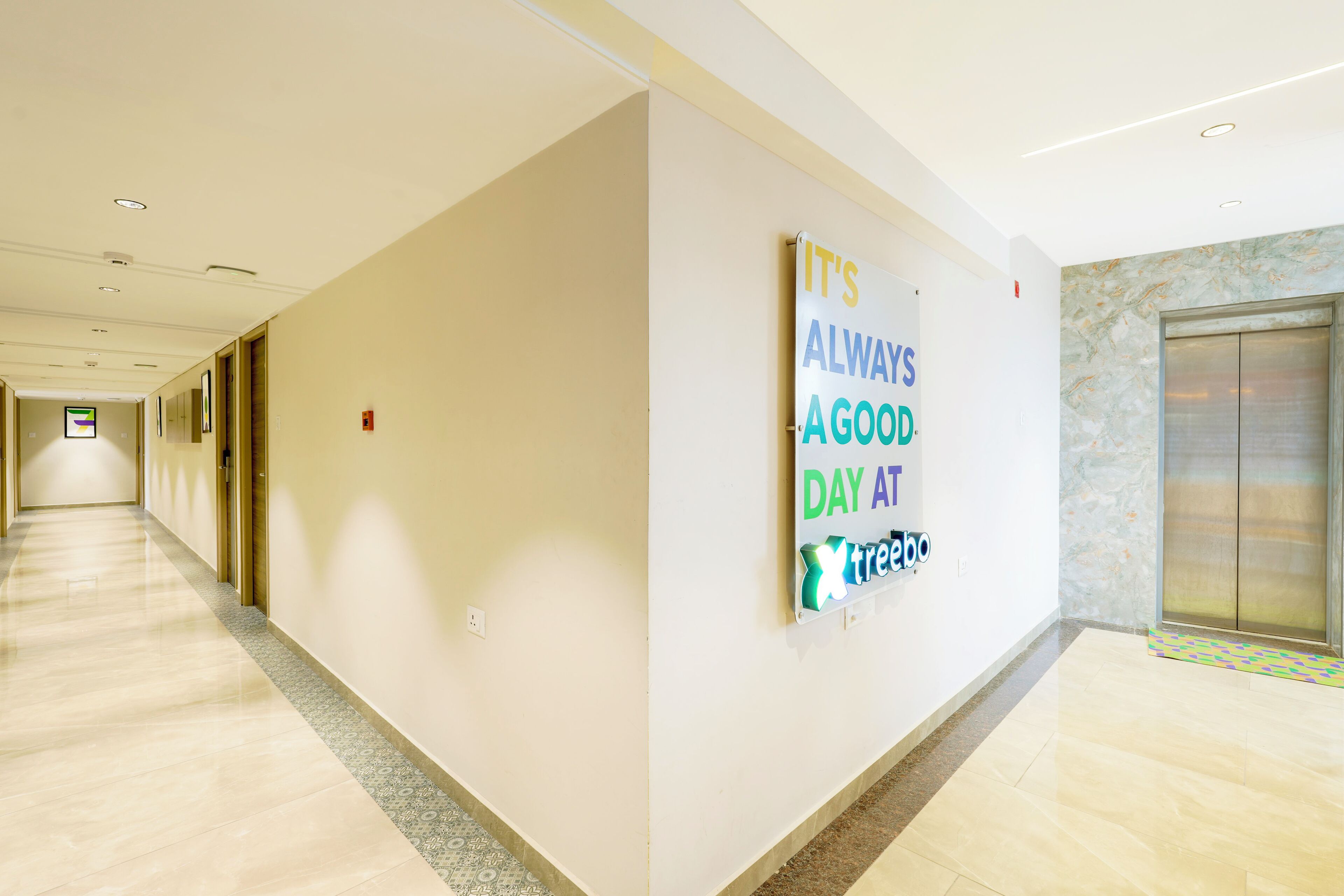 A hotel corridor with a motivational sign on the wall and an elevator.