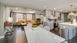 A modern kitchen with white cabinets, a central island, and stainless steel appliances. - Family Friendly: Modern Apt in Fort Washington (Fort Washington)