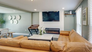 A living room with a large leather sofa, a fireplace, a flat-screen TV, and a dining area with a table and chairs. - Family Friendly: Modern Apt in Fort Washington (Fort Washington)