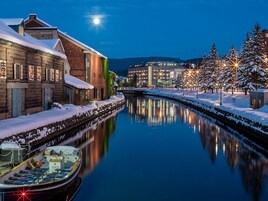 Un canal con un barco amarrado a la izquierda, edificios a ambos lados y árboles cubiertos de nieve.