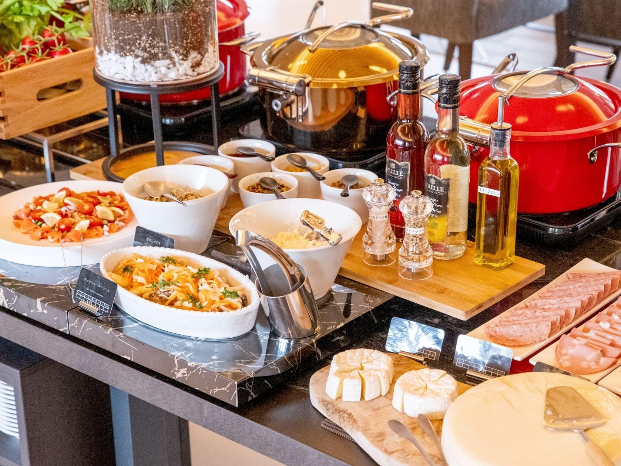 A buffet with various dishes, including salads, meats, and cheeses, along with condiments and cooking equipment.