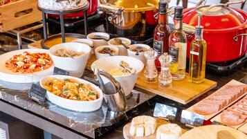 A buffet with various dishes, including salads, meats, and cheeses, along with condiments and cooking equipment.
