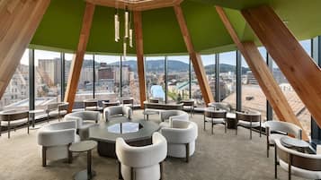 A modern conference room with a panoramic city view, featuring a unique wooden ceiling structure and comfortable seating.
