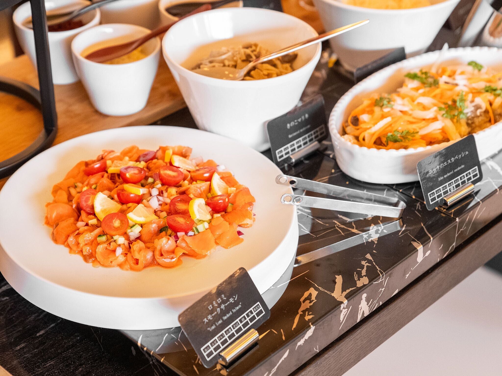 A buffet table with various dishes, including a salad, soup, and pasta.