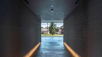 A hallway with a wet floor leading to a view of buildings and a tree.
