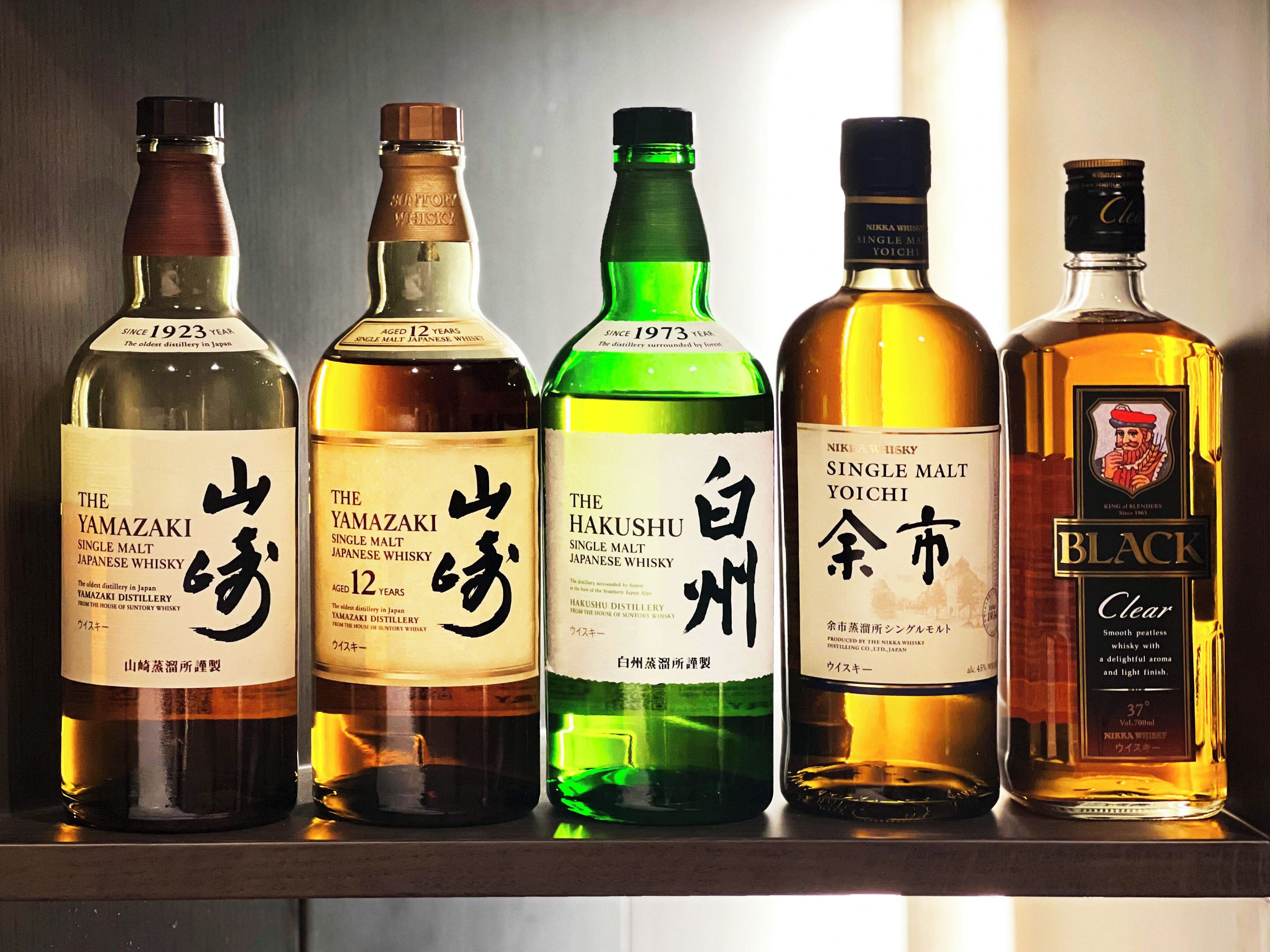 A row of five bottles of Japanese whisky on a shelf.