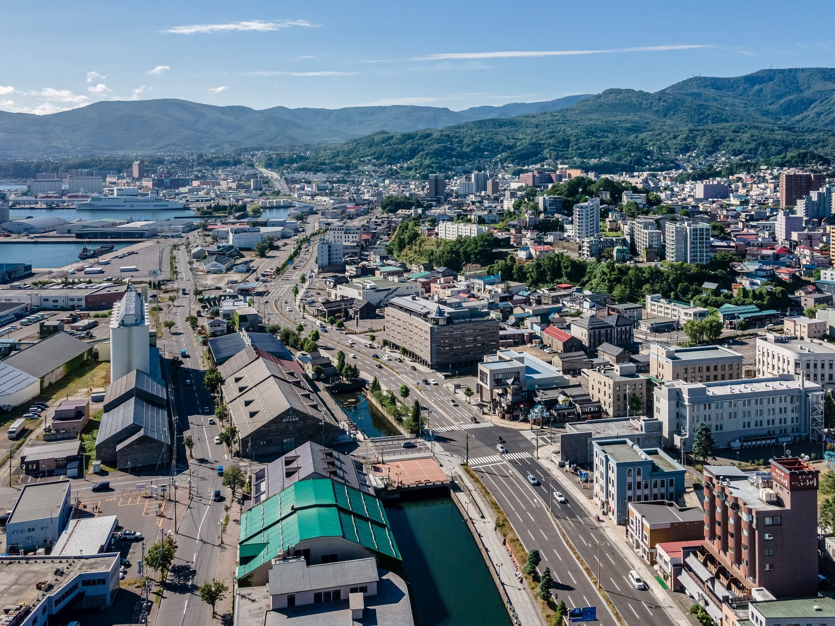 A cityscape with a river, buildings, and mountains in the background.
