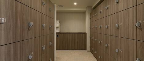 A row of wooden lockers with numbers on them, a white wall in the background, and a carpeted floor.