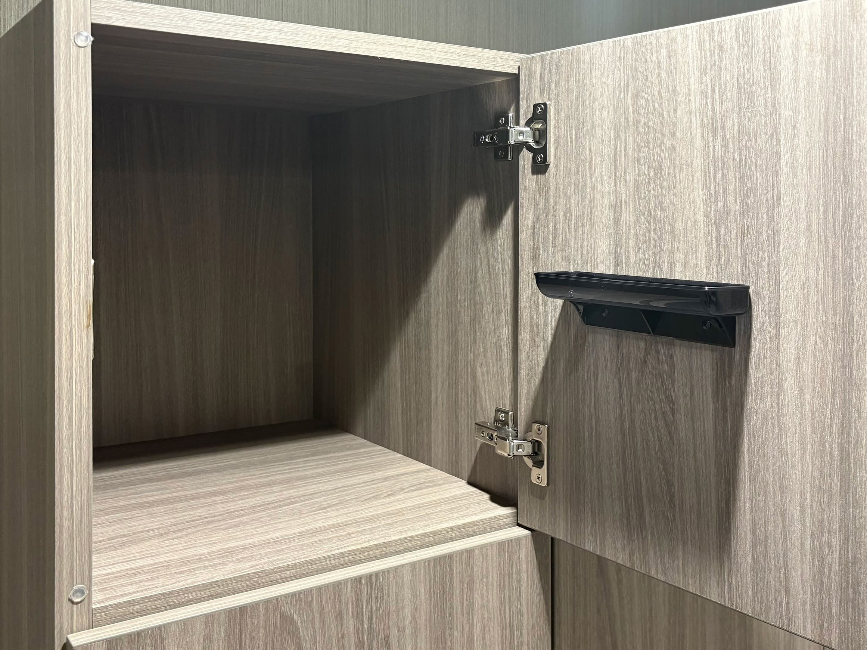 A wooden cabinet with a shelf and a small black object on top.