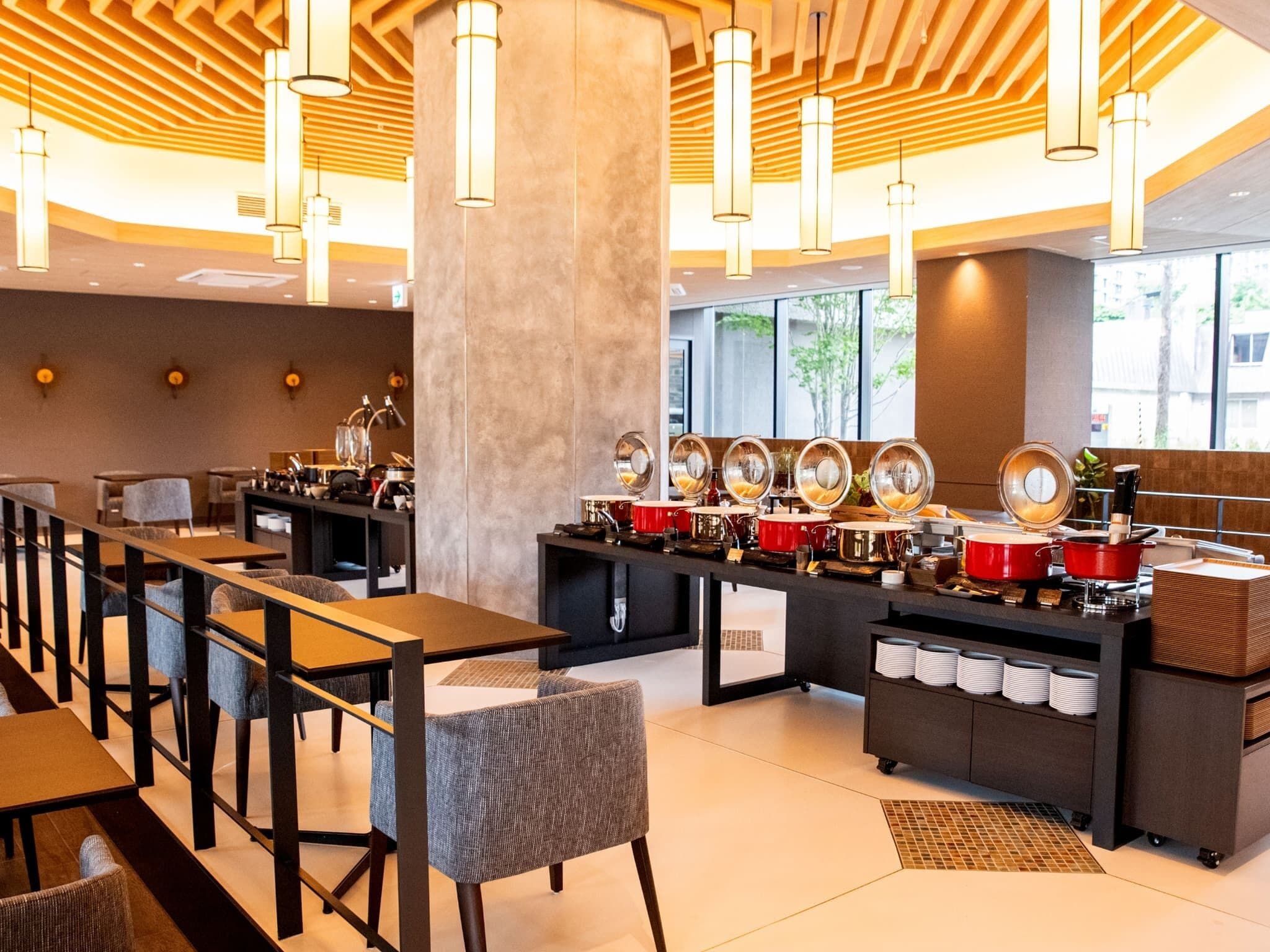 Un ristorante moderno con un lungo bancone, diversi tavoli e un'area buffet con varie pietanze.