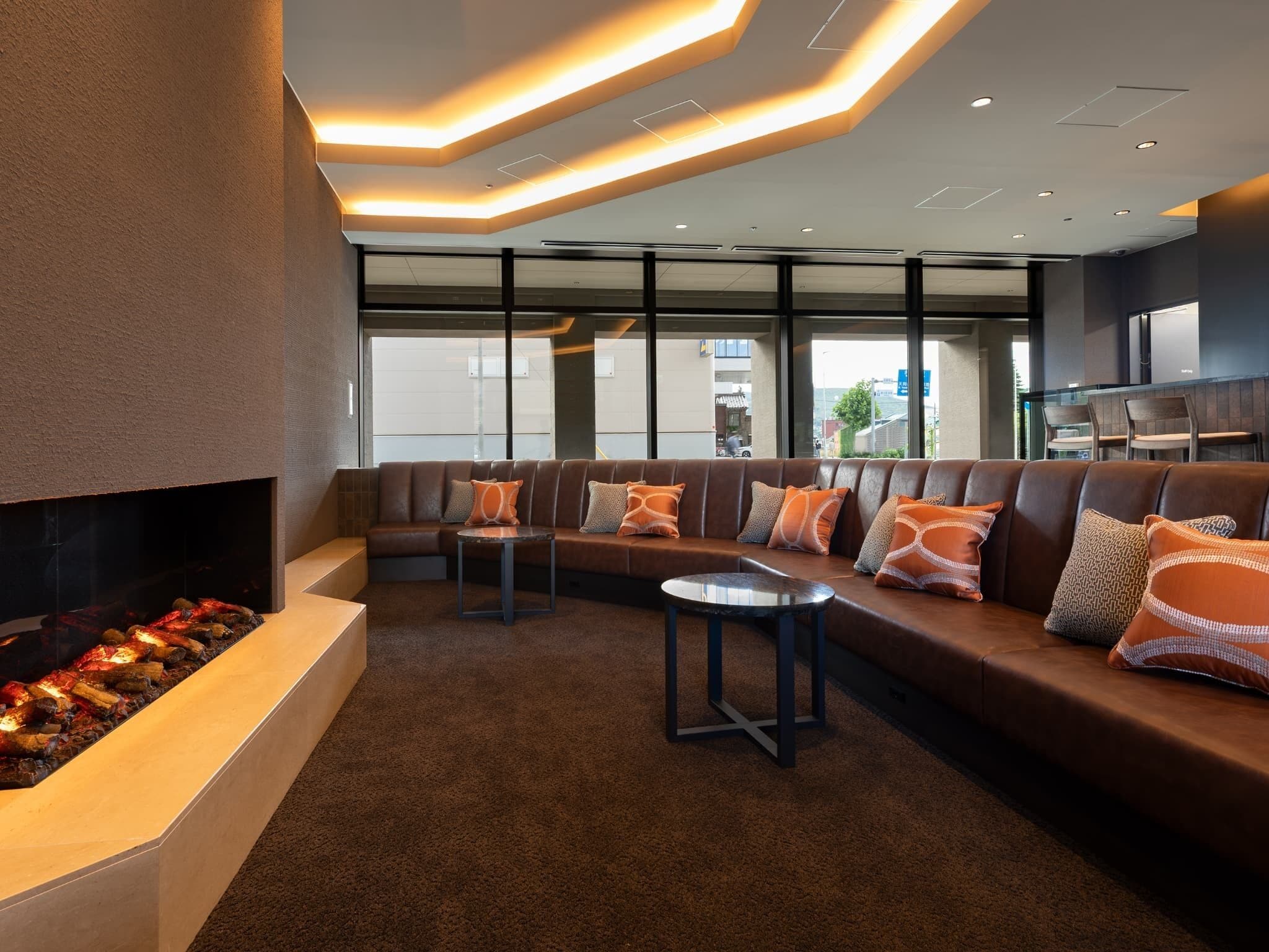 A modern lounge area with a built-in fireplace, leather seating, and a view of the city through large windows.