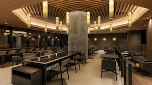 Een modern restaurant met een centrale bar, verschillende zithoeken en een opvallend plafondontwerp.