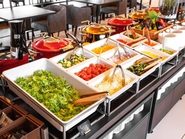 Un bufé con diversas opciones de comida, incluyendo ensaladas, verduras y carnes.