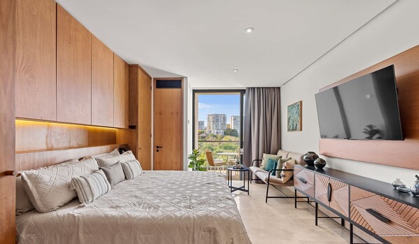 Ein modernes Schlafzimmer mit einem großen Bett, einem Fernseher und einem Balkon mit Blick auf die Stadt.