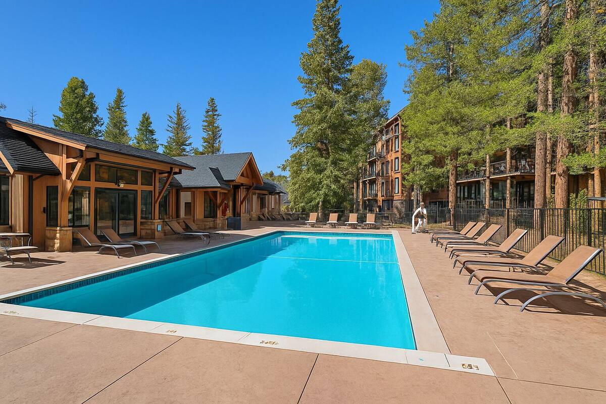 Une piscine avec des chaises longues et un bâtiment doté d’une façade en bois.