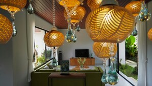 Un salon moderne avec des lampes suspendues, un canapé, un téléviseur et une vue sur l’extérieur.