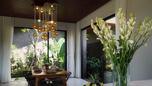 Un coin repas avec une table en bois, des chaises, un vase de fleurs et un luminaire suspendu.