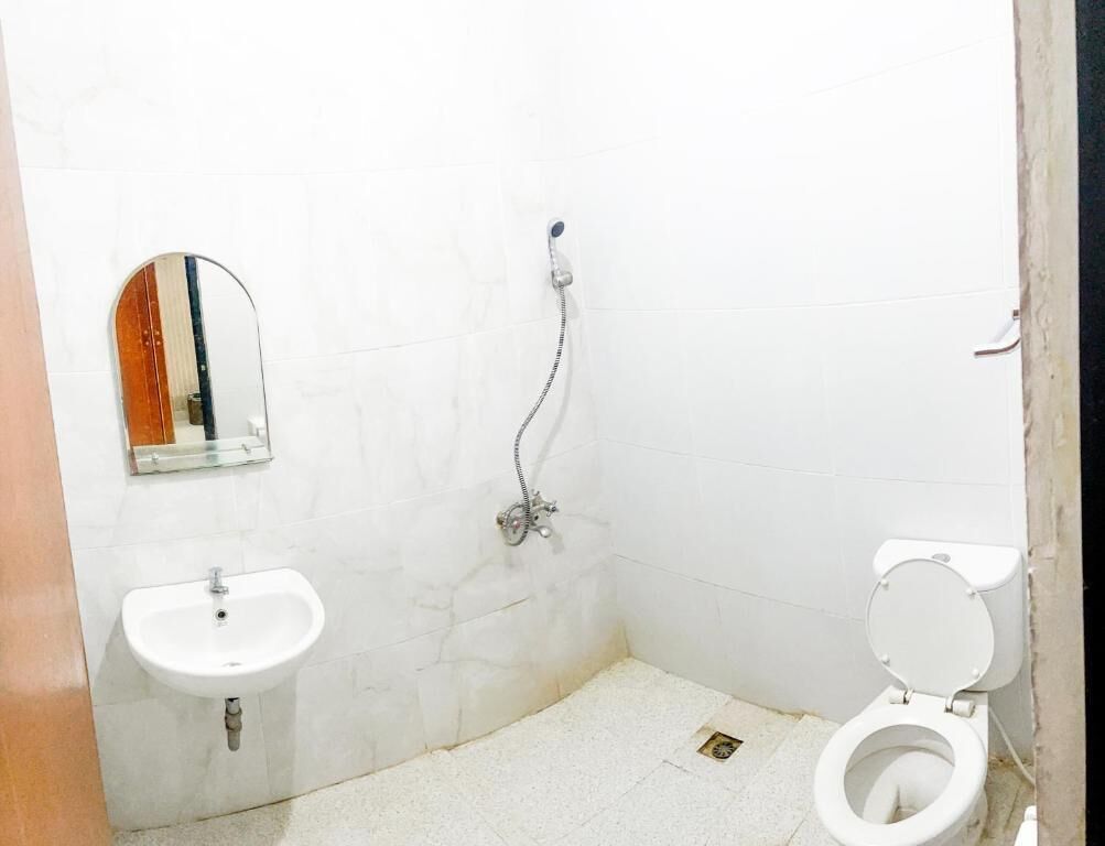 A small, white bathroom with a sink, mirror, and toilet.