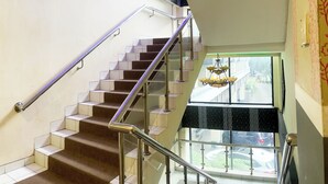 A modern interior with a staircase, glass railings, and a view of the outside. - Hotel Posters (Bandung)
