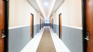 A long, narrow hallway with doors on both sides, leading to individual rooms. - Hotel Posters (Bandung)