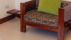 A room with a wooden sofa with a patterned cushion, a green pillow, and a wall adorned with circular woven art pieces. - Olive House - Private Pool, AC & Wi-Fi (Nungwi)