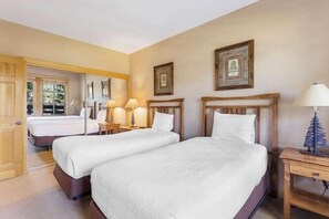 Camera d'albergo con due letti, una testiera in legno, comodini con lampade e quadri appesi alle pareti.