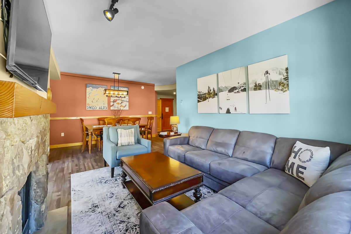 A modern living room with a sectional sofa, a coffee table, and a dining area with a wooden table and chairs.