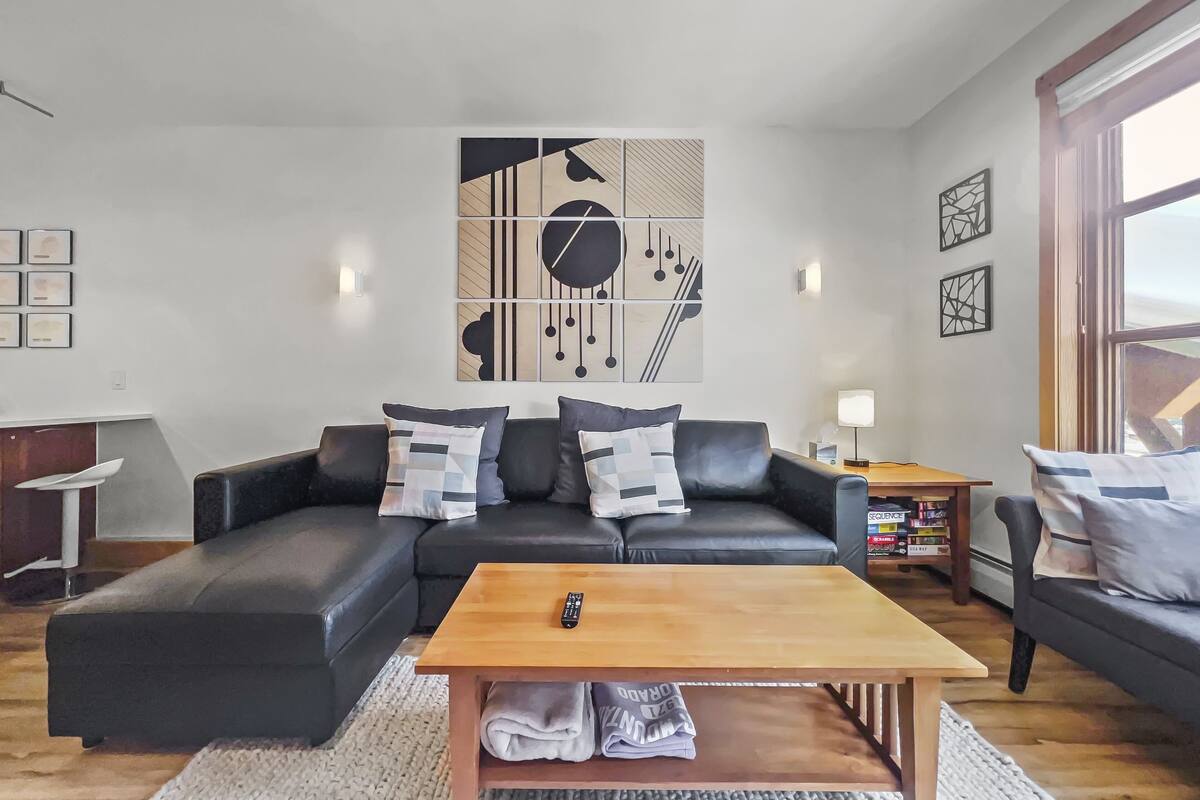 A modern living room with a sectional sofa, a wooden coffee table, and abstract wall art.