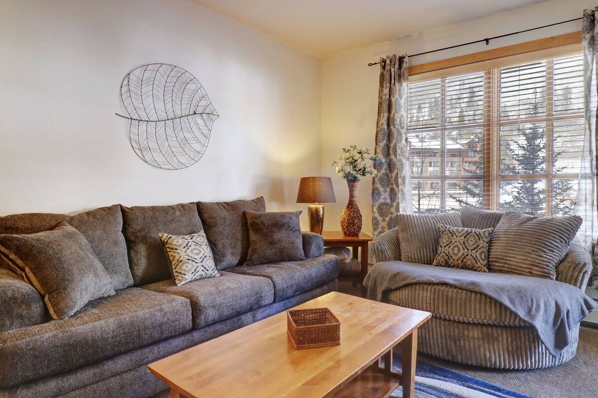 A cozy living room with a grey sofa, a wooden coffee table, and a patterned rug.