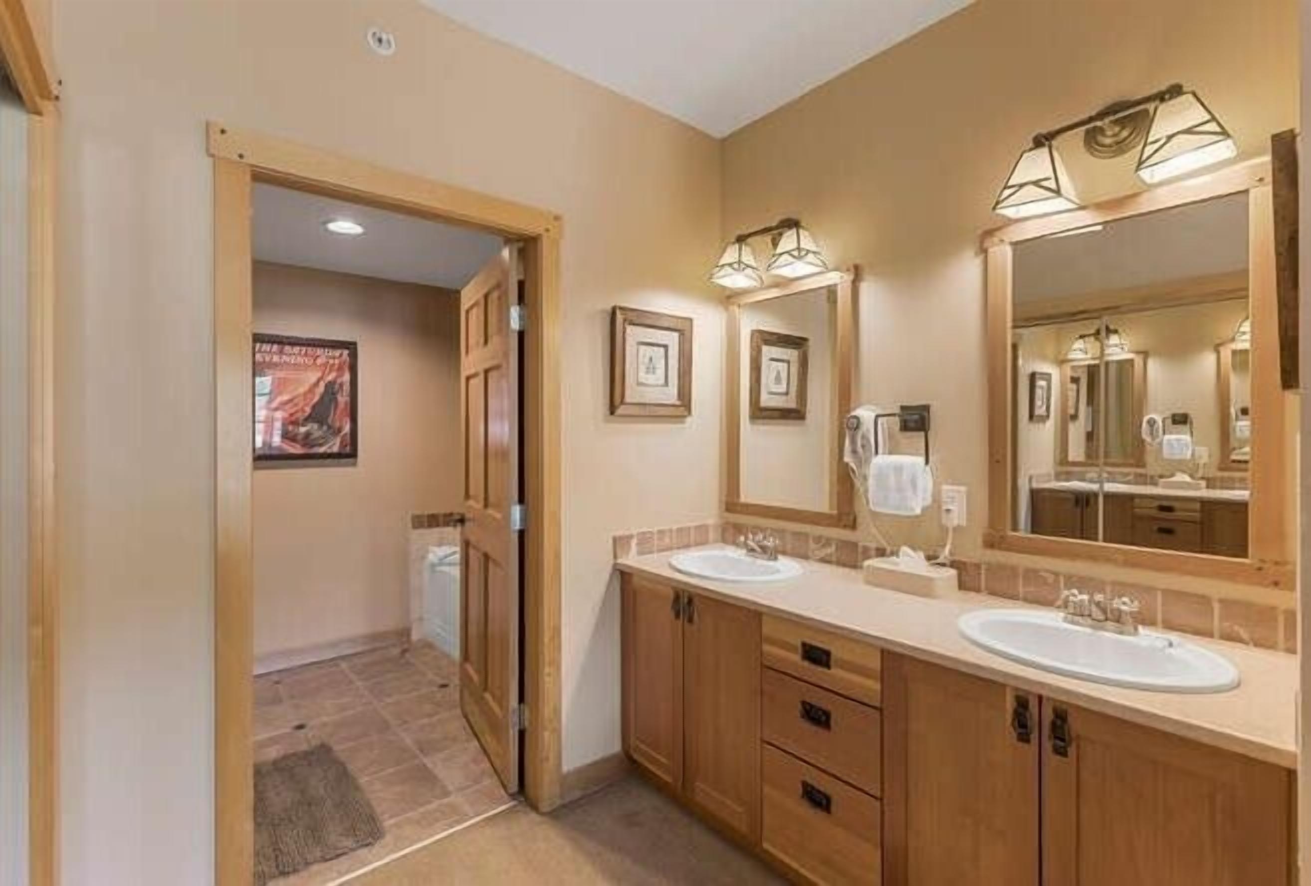 A bathroom with wooden cabinets, two sinks, and a large mirror.