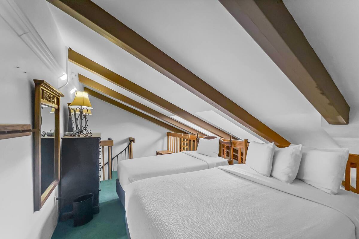 A bedroom with two beds, a mirror, a lamp, and a small table.