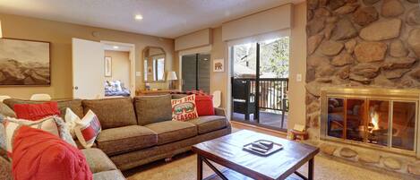 A cozy living room with a stone fireplace, a sofa, and a coffee table.
