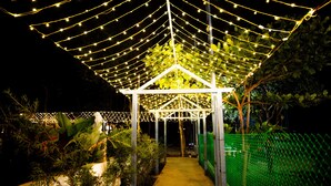 A covered outdoor area with string lights and a white structure. - Vanam Resort (Tupran)