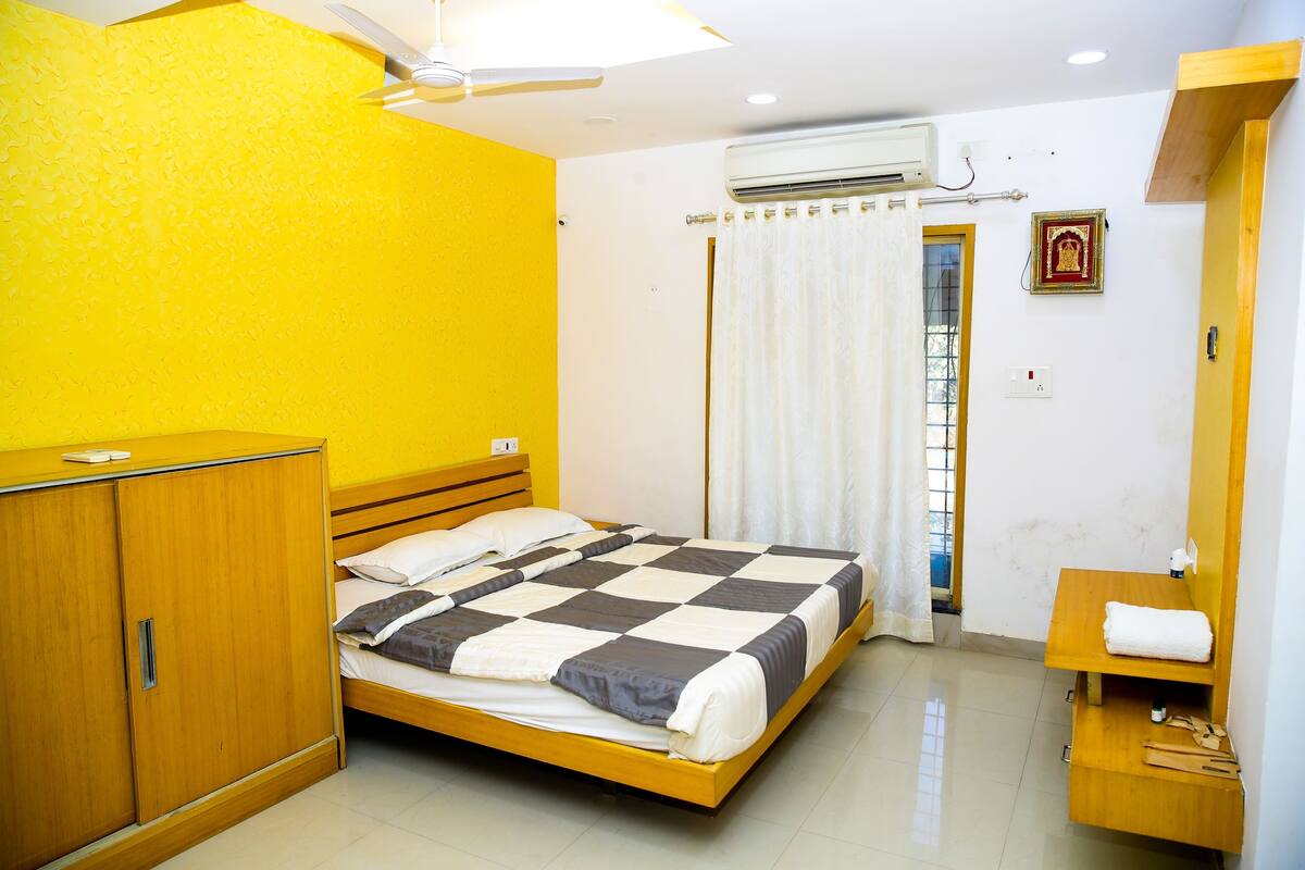A bedroom with a bed, wooden wardrobe, and a small wooden shelf with toiletries.
