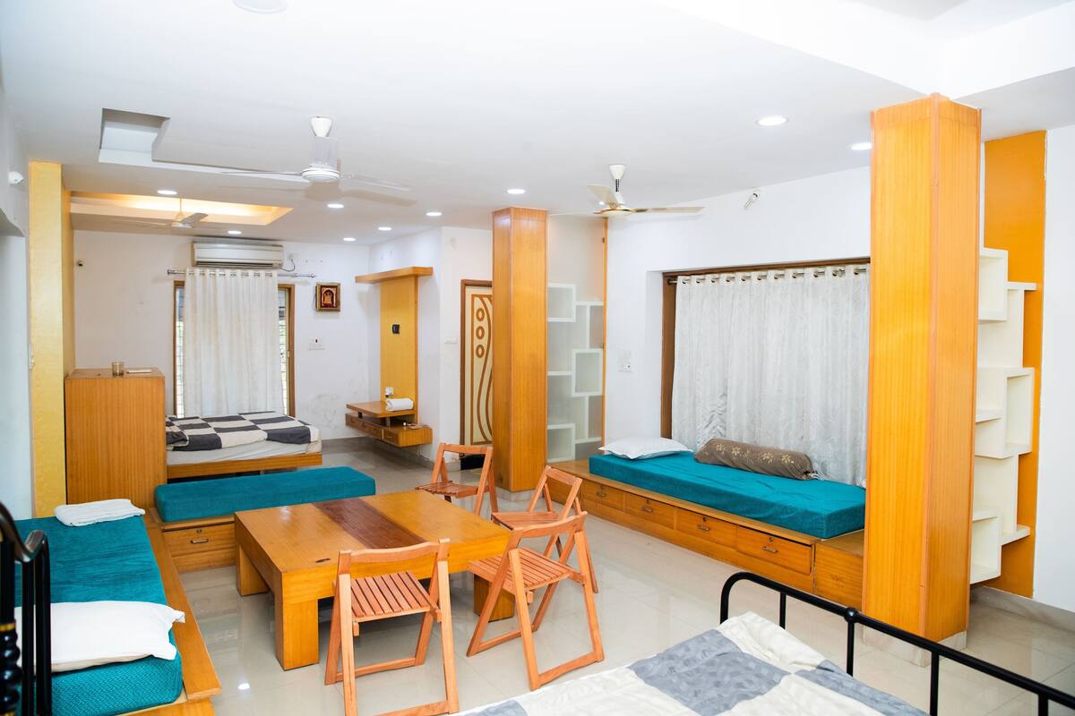 A modern, well-lit living room with a sofa, a wooden dining table, and a ceiling fan.