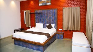A hotel room with a large bed, a wooden headboard, a small bedside table, and a bench. - Vanam Resort (Tupran)