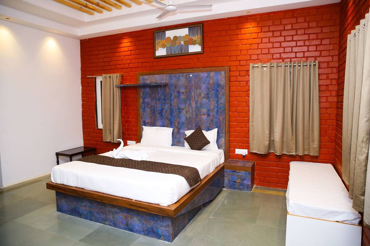 A hotel room with a large bed, a wooden headboard, a small bedside table, and a bench.