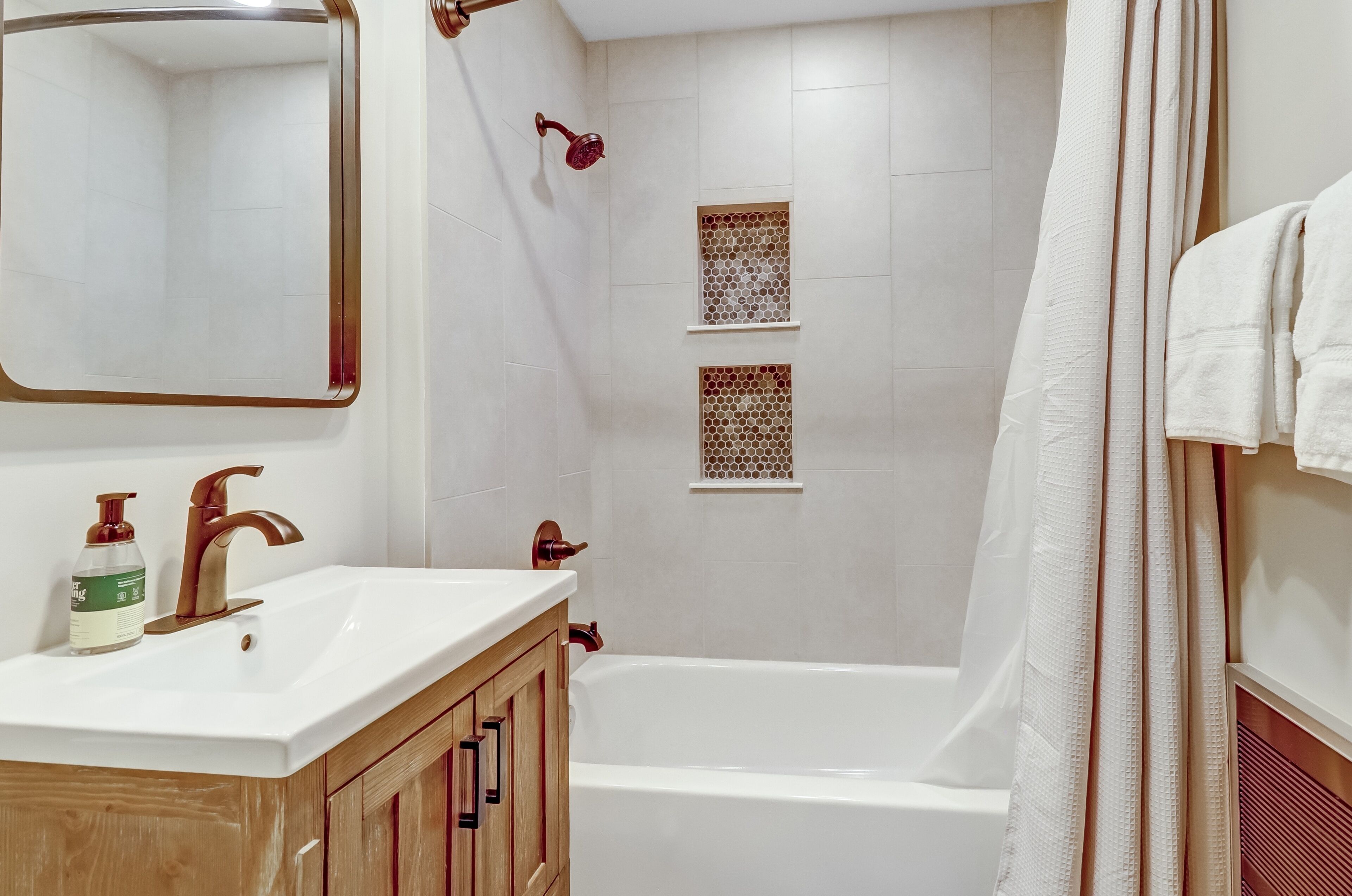 A bathroom with a white sink, wooden cabinet, and a bathtub.