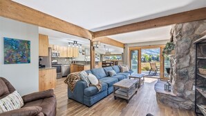 A spacious living area with a large blue sofa, wooden flooring, and a stone fireplace. - SkyRun Vacation Condos Copper Mountain Resort (Copper Mountain)