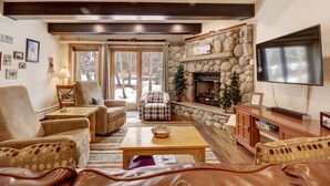A cozy living room with a stone fireplace, comfortable seating, and a television. - SkyRun - Copper Mountain Resort Vacation Condos (Copper Mountain)