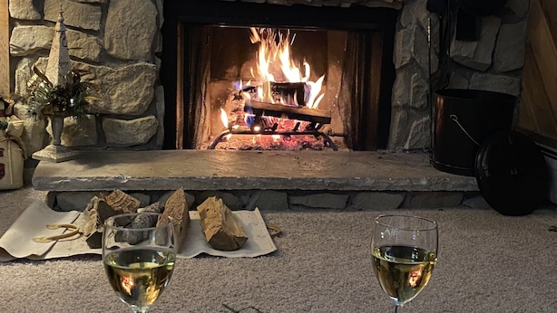 A stone fireplace with a fire, a plate of cheese and grapes, and two glasses of white wine on a table. - SkyRun - Copper Mountain Resort Vacation Condos (Copper Mountain)