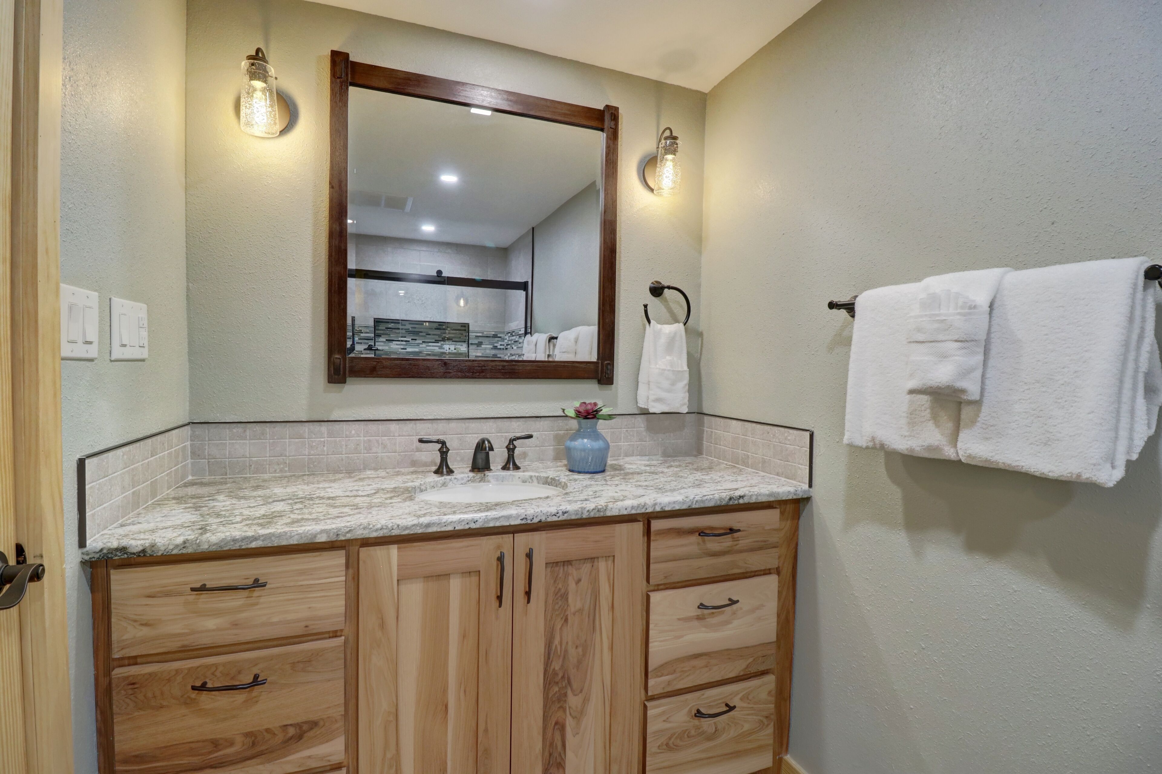 A bathroom with a wooden vanity, a large mirror, and a towel rack.