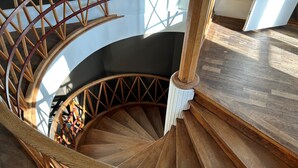 Un escalier en colimaçon en bois, doté d’une rampe blanche et d’une main courante en bois.